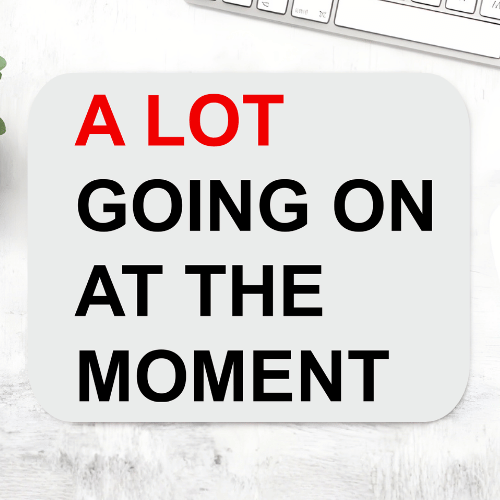 Taylor Swift A Lot Going On mousepad with bold red and black text 'A LOT going on at the moment' on a light grey rounded mouse pad – non-slip desk mouse mat, The Banyan Tee