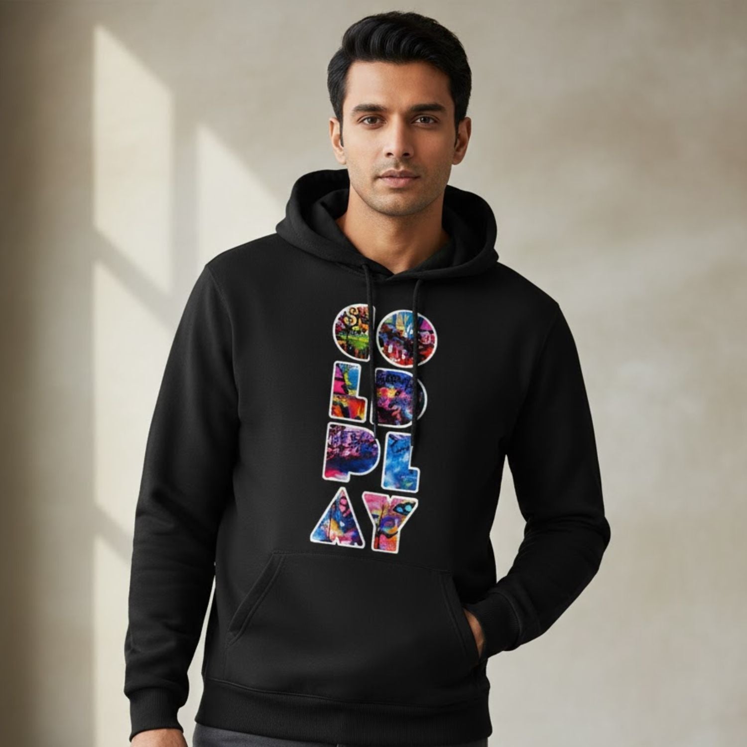 Man wearing a black hoodie with colorful text design on a neutral background
