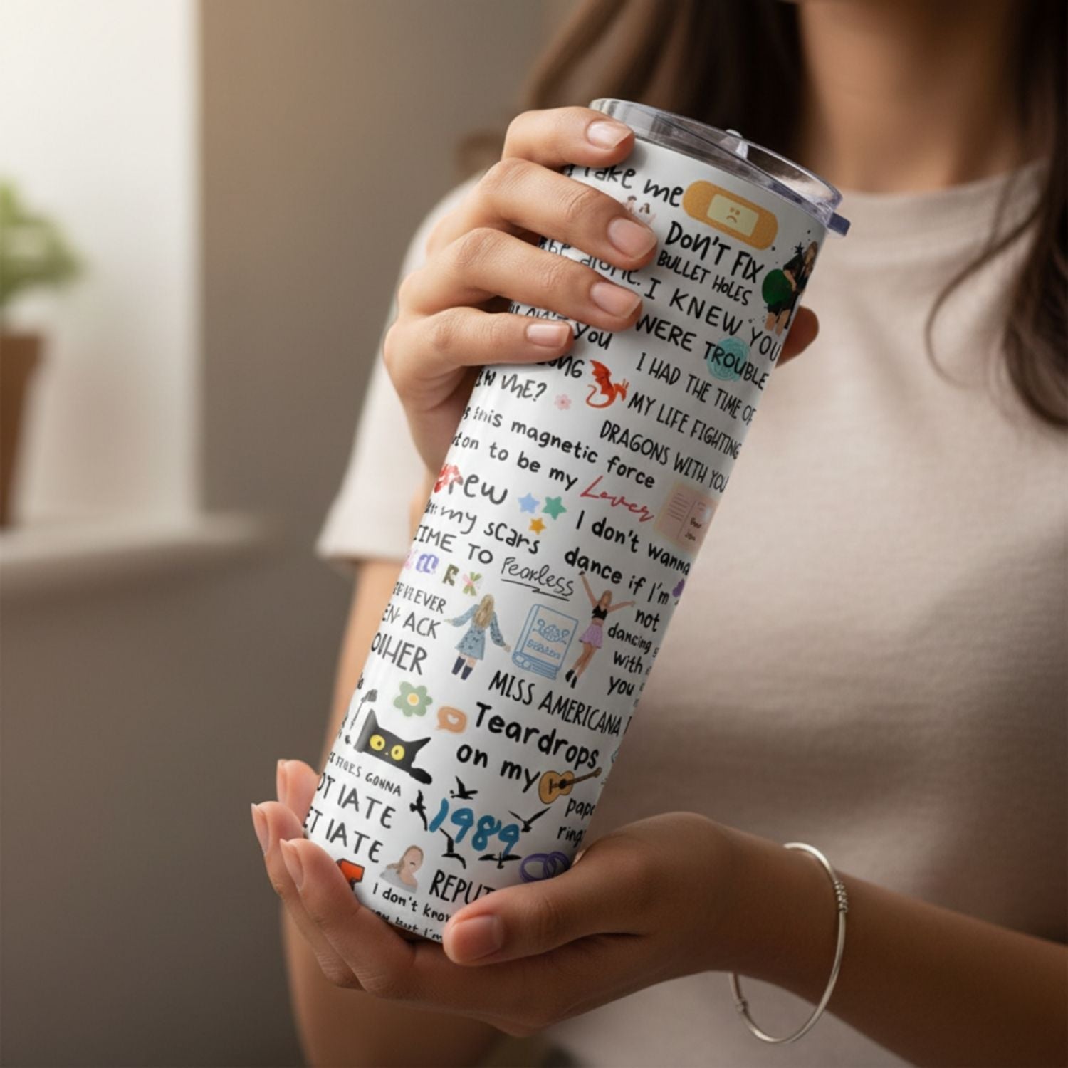Person holding a tumbler with a colorful design and text.