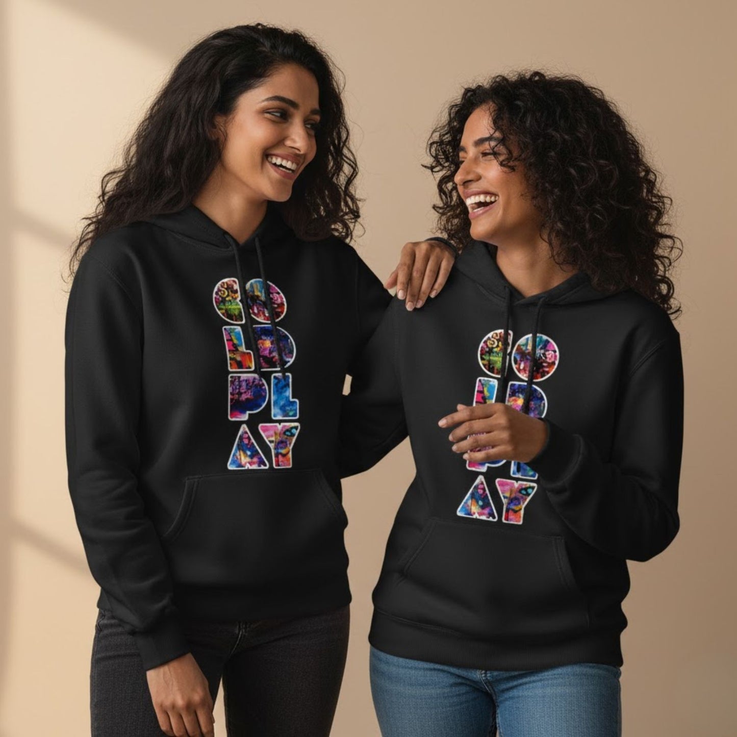 Two people wearing black hoodies with colorful text design on a beige background