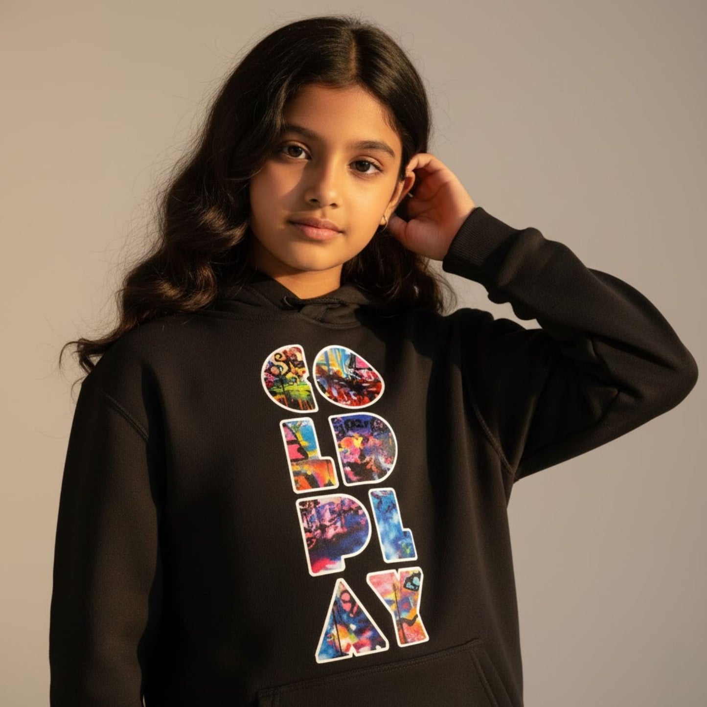 Child wearing a black hoodie with colorful text design on a plain background