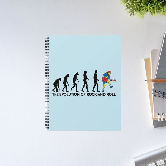 Notebook with 'The Evolution of Rock and Roll' design on a light blue cover, placed on a white surface. Notebook AC/DC The Banyan Tee