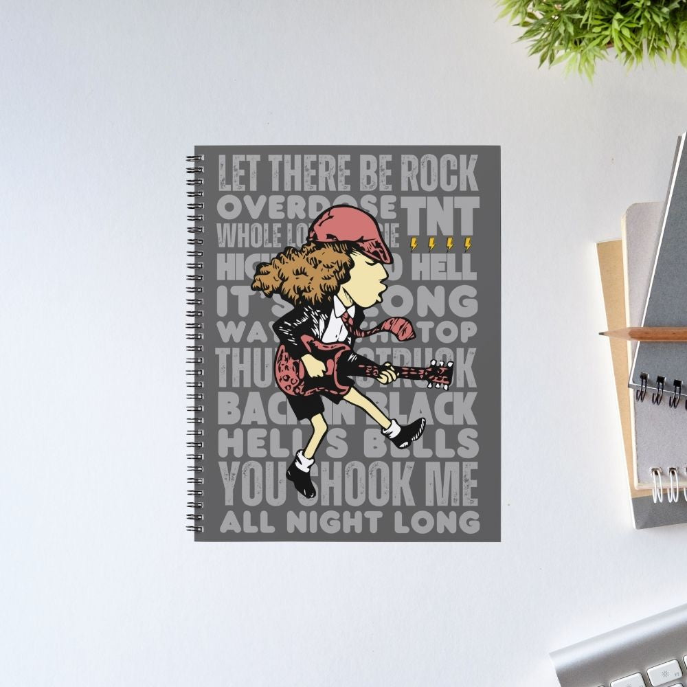 Notebook with a graphic design of a person playing guitar and lyrics on a gray background, placed on a light surface. Notebook AC/DC The Banyan Tee