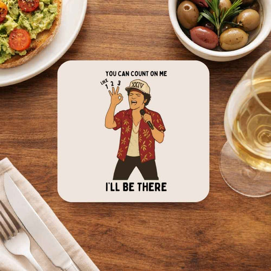 Coaster with a cartoon character and text on a wooden table with food and drink. Bruno Mars Gift The Banyan Tee India