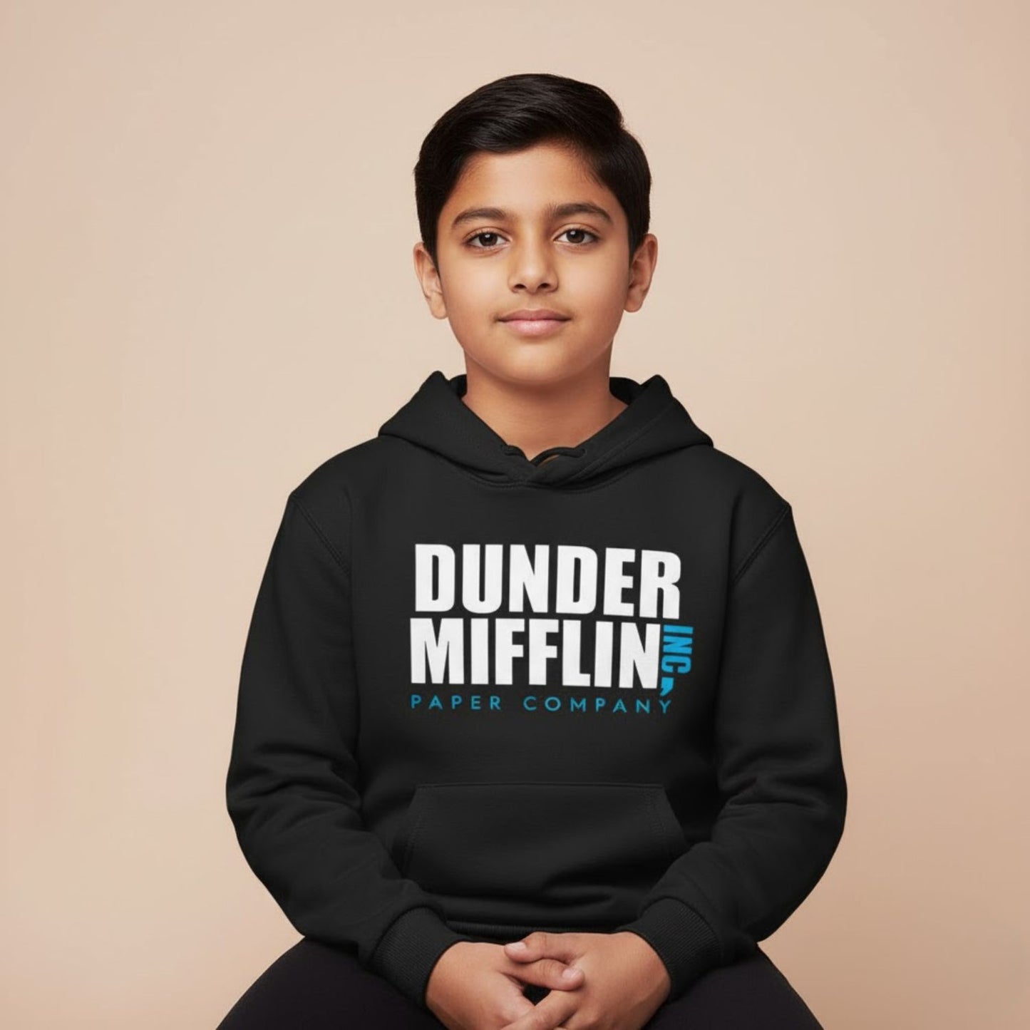 Person wearing a black hoodie with 'Dunder Mifflin Paper Company' text on a beige background