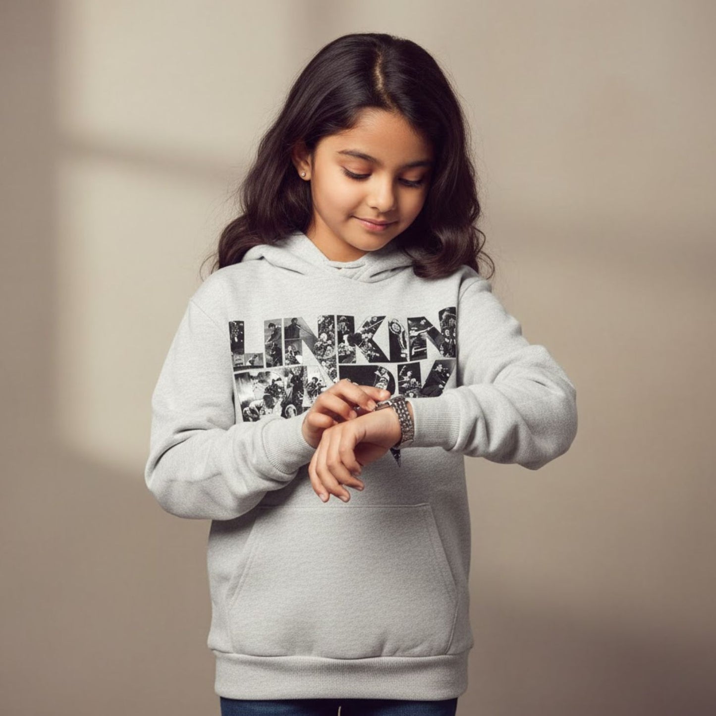 Young girl wearing a gray hoodie with 'Linkin Park' text, looking at her wristwatch.