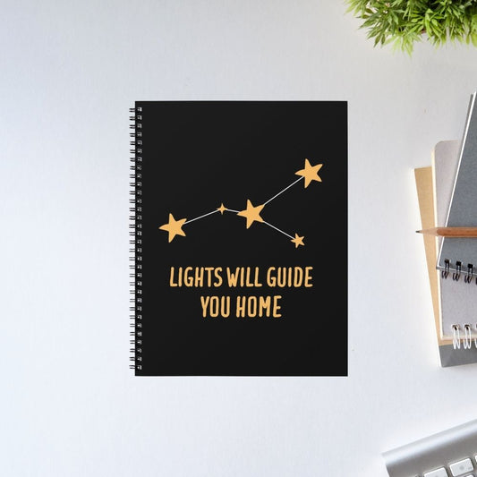 Black notebook with gold stars and text on a white surface Coldplay The Banyan Tee