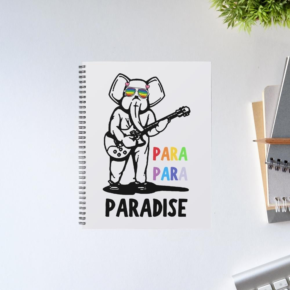 Notebook with an elephant playing guitar illustration and 'PARA PARADISE' text on a white surface. Coldplay The Banyan Tee