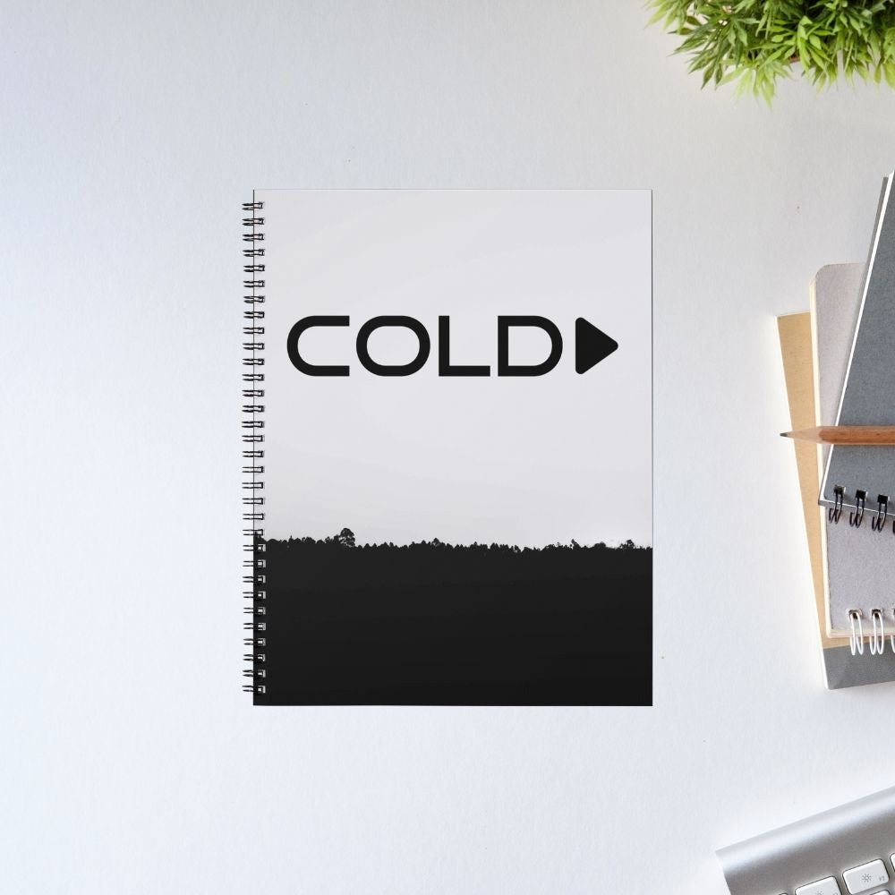 Notebook with 'COLD Play' text on a white surface with office items.  Coldplay The Banyan Tee