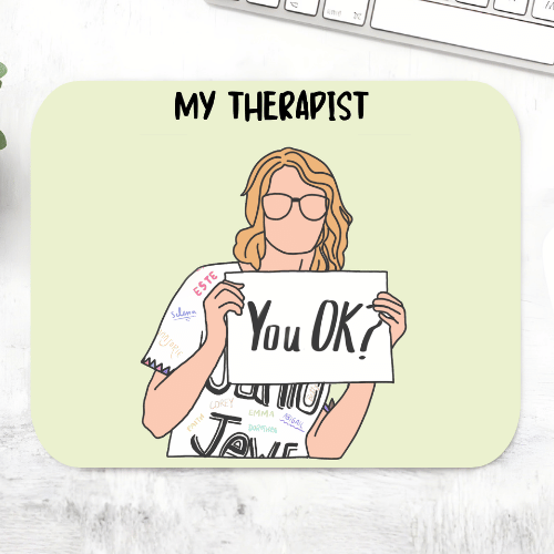 Taylor Swift My Therapist mousepad with a faceless illustrated woman in glasses holding a 'You OK?' sign on a pale green mouse pad – non-slip desk mouse mat, The Banyan Tee