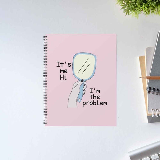 Taylor Swift Anti-Hero spiral notebook with a hand holding a mirror and the lyric 'It's me, hi, I'm the problem' on a pink cover – unruled notepad diary, The Banyan Tee