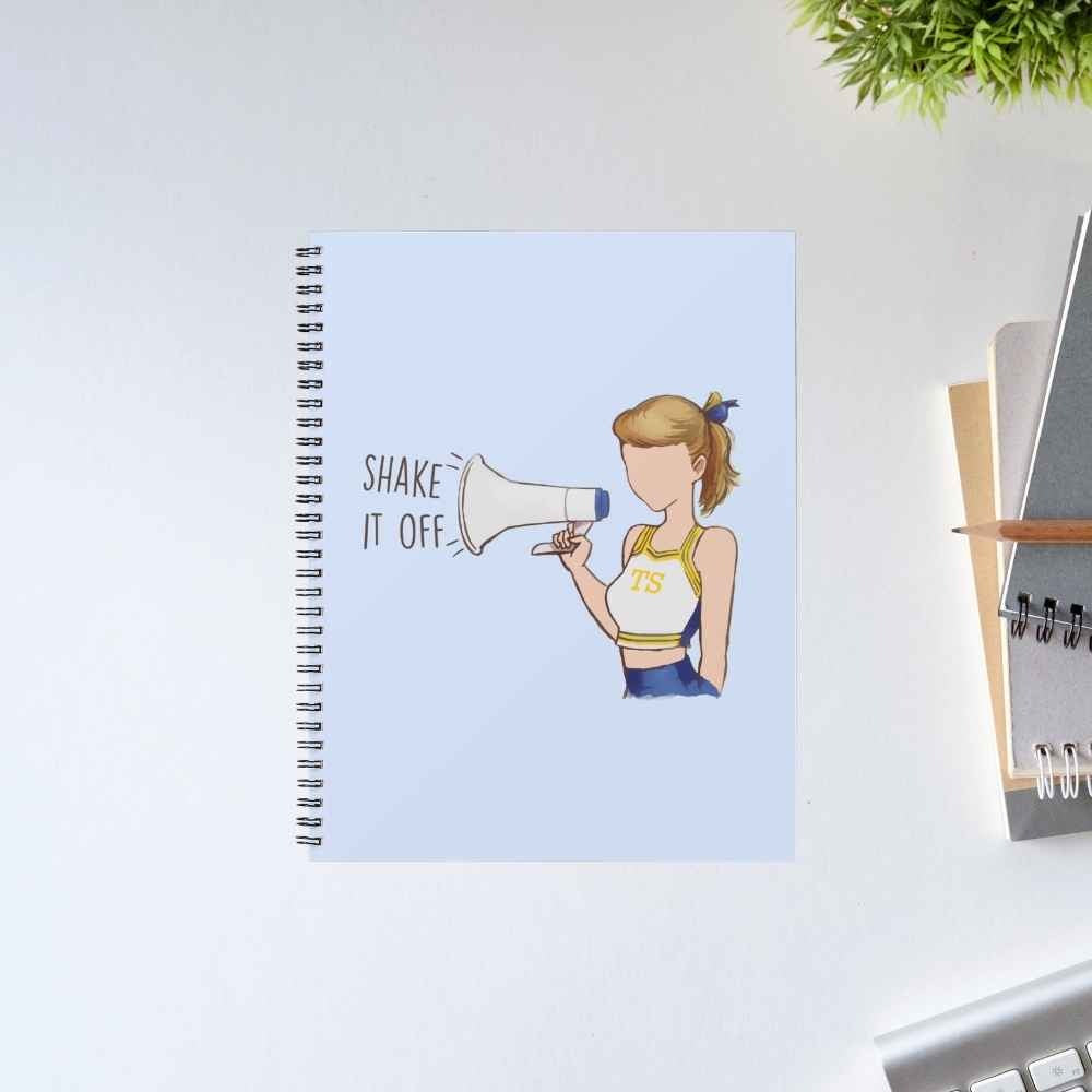 Taylor Swift Shake It Off spiral notebook with a cheerleader shouting through a megaphone on a light blue cover – unruled notepad diary, The Banyan Tee