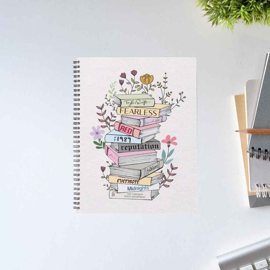 Taylor Swift The Tale of Tunes spiral notebook with a stack of album-spine books wrapped in wildflowers on an off-white cover – unruled notepad diary, The Banyan Tee