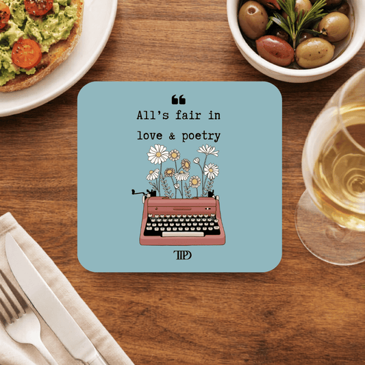 Taylor Swift All's Fair in Love & Poetry coaster with a rose-pink typewriter sprouting daisies and a TTPD logo, on dusty blue