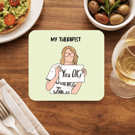 Taylor Swift My Therapist coaster with a faceless illustrated woman in glasses holding a You OK? sign, on pale green